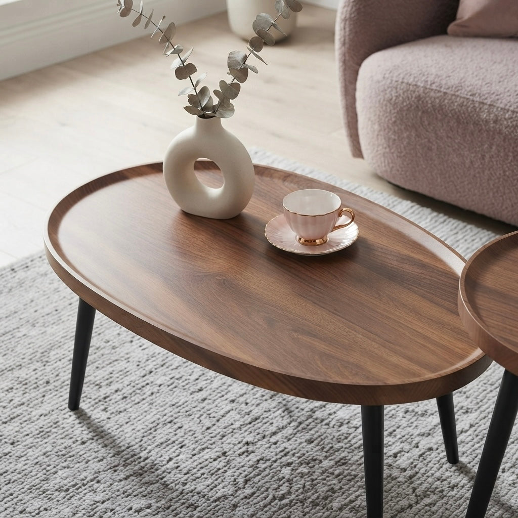 An oval wooden coffee table with black legs in a bright living room